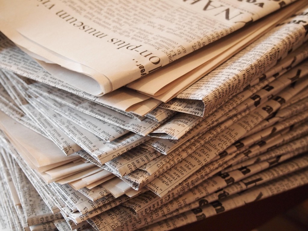 Image shows a stack of newspapers.